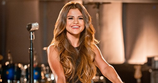 Selena Gomez sonriendo a la cámara en un estudio de grabación.